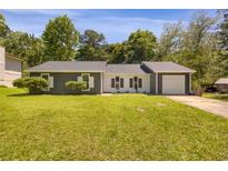 Charming one-story home features a well-maintained lawn, a covered front porch, and a driveway leading to a garage at 589 Wilmont Dr, Jonesboro, GA 30238
