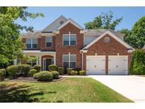 Traditional brick two-story home featuring a manicured lawn, an attached two-car garage and mature trees at 130 Bevington Ln, Woodstock, GA 30188