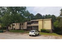 Quaint two-story apartment building with tan and yellow siding nestled among mature trees and green lawns at 5931 Sutcliff Sq, Lithonia, GA 30058