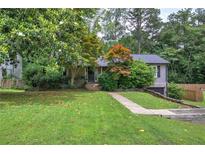 Charming single-Gathering home featuring lush front lawn, mature trees, and a welcoming exterior at 1837 Lochlomand Se Ln, Smyrna, GA 30080