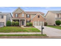 Beautiful brick home with a manicured lawn and two-car garage at 3476 Bridge Walk Drive, Lawrenceville, GA 30044