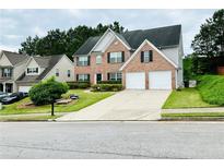 Traditional two-story brick home featuring a two-car garage and well-manicured lawn at 665 Roxford Ln, Buford, GA 30518