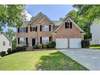 Charming two-story brick home with well-manicured lawn and a two-car garage at 3805 Roxwood Park Dr, Buford, GA 30518