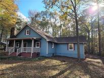 Charming blue home featuring a stone chimney and a welcoming front porch at 125 Toccoa Rd, Carrollton, GA 30116