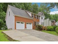 Charming two-story home with a brick facade, two-car garage, and a well-manicured front yard, complemented by lush greenery at 1369 Willowbrook Sw Dr, Marietta, GA 30064