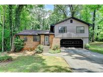 Charming split-level home featuring a brick facade, attached garage, and a lush, wooded lot at 262 Somerset Ct, Lawrenceville, GA 30044