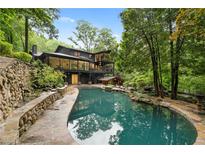 An entertainer's dream backyard featuring a unique shaped pool, natural rock waterfall, mature landscaping and a modern home at 4601 Tall Pines Nw Dr, Atlanta, GA 30327