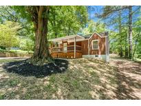 Charming brick home featuring a cozy front porch and beautiful landscaping around a mature tree at 2174 Rexford Dr, Decatur, GA 30034