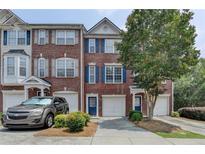 Brick townhome with blue shutters, attached garages, and mature landscaping provides great curb appeal at 3187 Mill Springs Cir, Buford, GA 30519