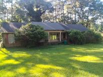 Lawn view of the home, a single-story house with an overgrown yard and mature trees at 1627 Norden Rd, Riverdale, GA 30296