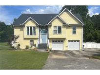 Charming yellow two-story home featuring an attached two-car garage and an inviting blue front door at 17 Country Walk, Cartersville, GA 30121