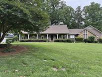 Charming home featuring a beautiful manicured lawn, mature trees, and inviting front porch with decorative plants at 12162 Mountain Laurel Dr, Roswell, GA 30075