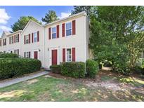 Inviting townhouse featuring neutral siding, complemented by red shutters and a well-maintained front lawn and mature trees at 3371 Spring Harbour Dr, Atlanta, GA 30340