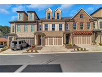 Three-story townhome exterior featuring a two car garage and well maintained landscaping at 118 Via Roma, Woodstock, GA 30188