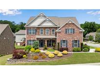 Stunning brick home features mature landscaping, a well-manicured lawn, and charming architectural details at 431 La Perla Dr, Sugar Hill, GA 30518
