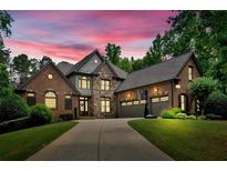 Stunning brick home with stone accents, three-car garage, basketball hoop, and well-manicured lawn at 511 Etris Ct, Roswell, GA 30075