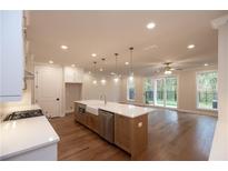 Modern kitchen with an island, stainless steel appliances, and hardwood floors leading to a room with sliding glass doors at 512 Winston Croft Cir # 56, Johns Creek, GA 30022