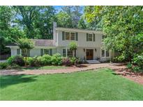 Charming two-story home featuring a well-manicured lawn, mature trees, and classic architectural details at 435 Grenock Cir, Atlanta, GA 30328