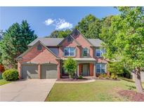 Charming brick two-story home with a three-car garage and well-manicured lawn at 5115 Amberden Hall Dr, Suwanee, GA 30024