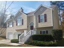 Two-story home featuring neutral siding, complementary shutters, well-maintained landscaping, and an attached two-car garage at 5709 Newnan Cir, Austell, GA 30106