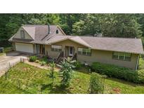 Charming home featuring a welcoming front porch, attached garage, and lush green surroundings at 2026 Mcdaniel Mill Sw Rd, Conyers, GA 30094