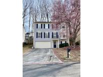 Two-story home with a two-car garage, manicured lawn, and tree with vibrant pink blossoms at 5105 N Bridges Dr, Alpharetta, GA 30022