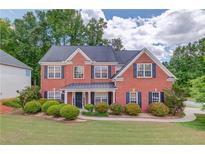 Charming two-story brick home with a well-manicured lawn and lush landscaping at 1657 Hampton Woods Way, Lawrenceville, GA 30043