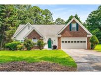 Charming two-story home with brick accents, a green door, a two-car garage, and a well-manicured lawn at 1978 Elmwood Cir, Snellville, GA 30078