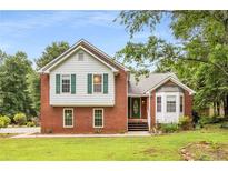Charming two-story brick home featuring a bay window, green shutters, and a well-manicured lawn and landscape at 524 Stephens Point Se Dr, Lawrenceville, GA 30045