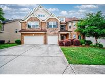 Beautiful two-story brick home with a two-car garage, landscaped front yard, and inviting entrance at 3740 Lake Enclave Way, Atlanta, GA 30349