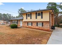 Charming two-story home with a brick and yellow siding, surrounded by mature trees and a well-maintained lawn at 2002 Twin Falls Rd, Decatur, GA 30032