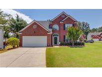 Charming brick two-story home with a well-manicured lawn and a two-car garage on a sunny day at 2990 Haynes Club Cir, Grayson, GA 30017