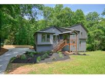 Charming home featuring a welcoming front porch, a well-manicured lawn, and a driveway leading to a spacious garage at 3427 Mill Stream Sw Ln, Marietta, GA 30060