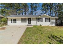 Charming single-story home featuring a well-maintained lawn and freshly painted white exterior at 80 Crystal River Dr, Riverdale, GA 30274