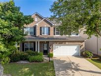 Charming two-story brick home with a well-manicured lawn, mature trees, and a two-car garage at 5909 Rue Chase Way, Tucker, GA 30084