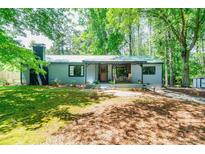 Charming home with well-maintained lawn, covered porch, metal roof, and mature trees offering shade at 391 Buchanan St, Dallas, GA 30157