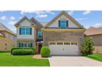 Charming two-story home featuring a brick facade, attached two-car garage, lush lawn, and manicured hedges at 2185 Creole Cir, Cumming, GA 30040