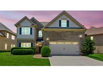 Two-story home with manicured lawn, brick accents, two-car garage, and a pathway to the front door at 2185 Creole Cir, Cumming, GA 30040