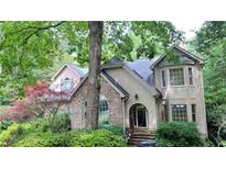 Charming home featuring a stone facade, arched entry, dormer windows, and lush, mature landscaping at 5357 Steeple Chase, Douglasville, GA 30135