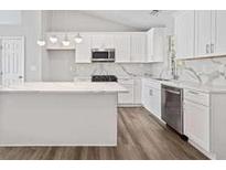 Bright kitchen features white cabinetry, stainless steel appliances, an island and marble countertops at 5950 Milligan Ct, Atlanta, GA 30349