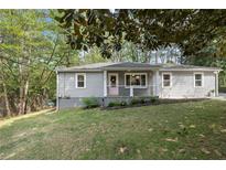 Charming single-story home featuring gray siding, a pink front door, and well-maintained landscaping at 5725 Brenda Sw Dr, Mableton, GA 30126