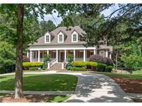 Stunning two-story home with a grand front porch, manicured lawn, and a circular driveway nestled amongst mature trees at 100 Trotters Ridge, Fayetteville, GA 30215