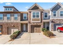 Charming townhome features a brick facade, inviting front door, attached garage and well-maintained landscaping at 2309 Rolling Trl, Lithonia, GA 30058
