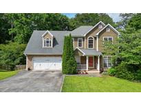 Charming two-story home featuring a stone and vinyl facade, two-car garage, and well-manicured lawn at 2004 Spicers Ln, Woodstock, GA 30189