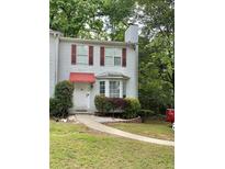 Charming two-story townhome with red awnings, manicured landscaping, and a stone walkway leading to the front door at 1104 Huntington Se Trce, Smyrna, GA 30082
