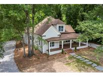 Charming home with covered porch, stone walkway, beautiful landscaping, and mature shade trees at 159 S Forest S Ave, Social Circle, GA 30025
