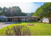 Charming brick home featuring a covered porch and carport, surrounded by a lush green lawn and mature trees at 1526 Tanglewood Nw Way, Conyers, GA 30012