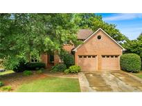 Charming brick home featuring a two-car garage, mature landscaping, and a welcoming entrance at 1593 Poplarwood Lane Northwest Ln, Lawrenceville, GA 30043