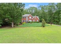 Charming red brick home with manicured lawn and mature trees offers inviting curb appeal at 9048 River Bend Ct, Villa Rica, GA 30180