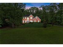 Traditional brick home with a manicured lawn and mature trees at dusk at 9048 River Bend Ct, Villa Rica, GA 30180